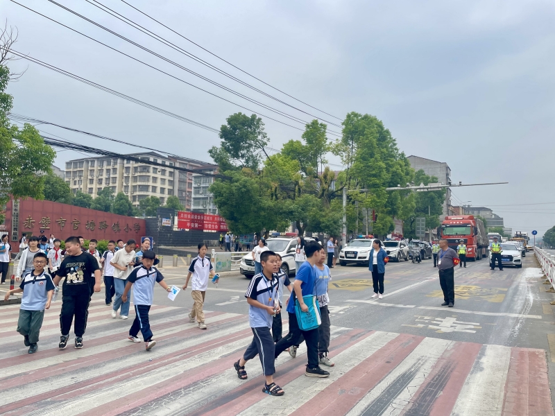 官塘驛中隊(duì)交警截停車流，形成安全屏障，守護(hù)小學(xué)生上放學(xué)路。